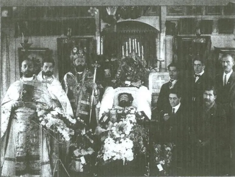 Father Nicola lying in state before the iconostasis, with a bishop, clergy and parishioners standing beside him